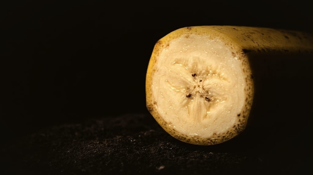 A Gros Michel banana cut open on volcanic rock, showing dense, creamy, custard-like flesh